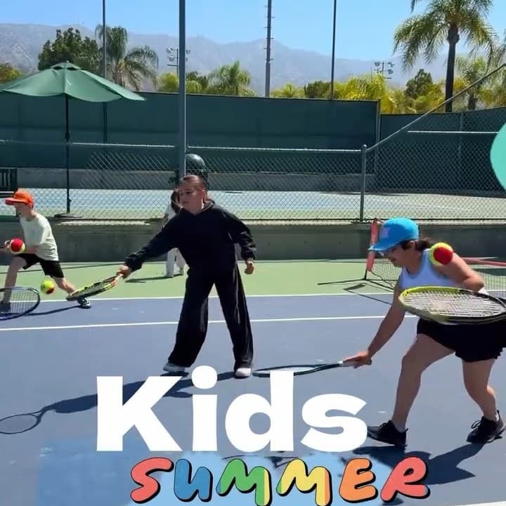 Kids with rackets at a summer tennis lesson